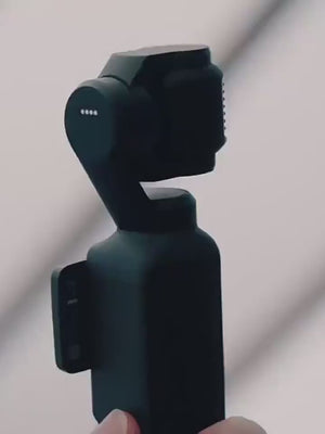 A close-up view of the sleek black design and rotating stabilization axes of the DJI Osmo Pocket 4 handheld camera.