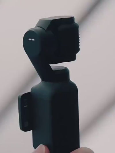 A close-up view of the sleek black design and rotating stabilization axes of the DJI Osmo Pocket 4 handheld camera.