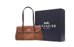 شعار Coach المعدني الذهبي على واجهة الحقيبة