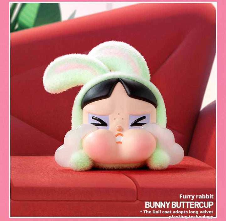دمية باني باتركب من POP MART Crybaby بتصميم أرنب فروي ولون أخضر فاتح على أريكة حمراء.