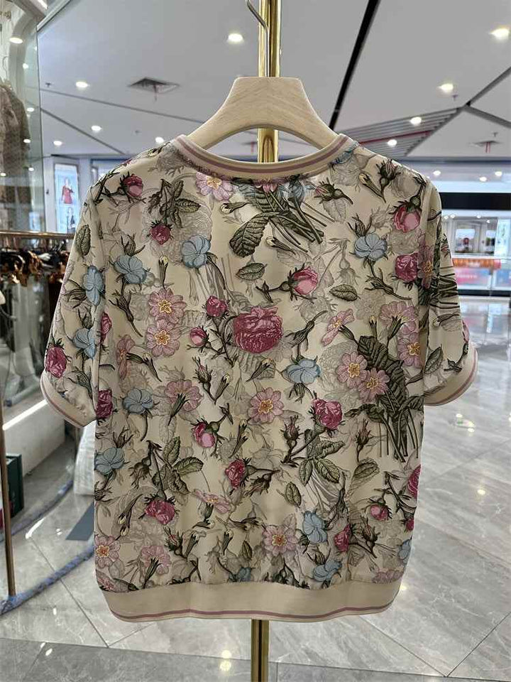 Women's loose floral silk blouse with soft colors on beige background, perfect for summer.