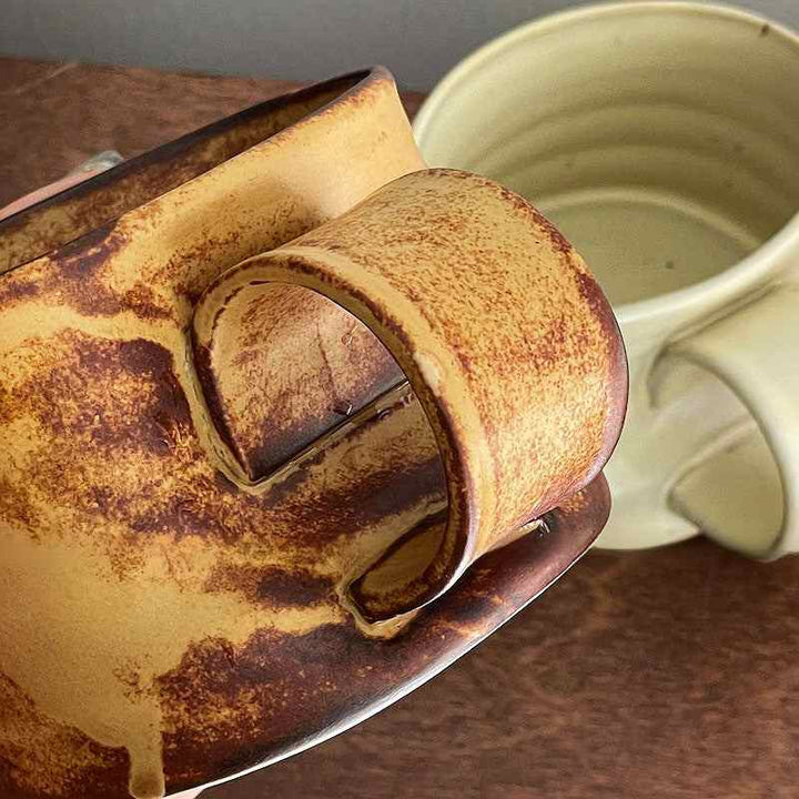 كوب فخار مائل يدوي بتصميم ريفي أنيق ولون بني عسلي دافئ.