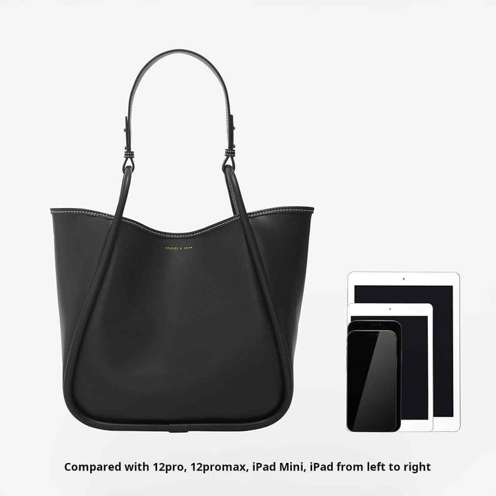 Black large Charles & Keith shoulder bag made of premium faux leather, spacious with adjustable long strap, shown next to 12 Pro, 12 Pro Max, iPad Mini, and iPad for size comparison.