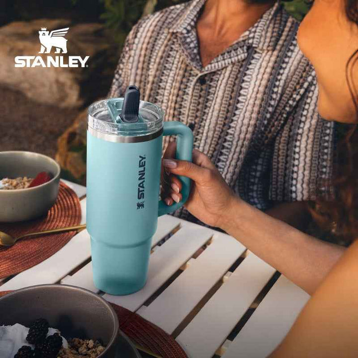Stanley insulated stainless steel travel mug with handle and leak-proof lid in light blue, perfect for hot and cold drinks.