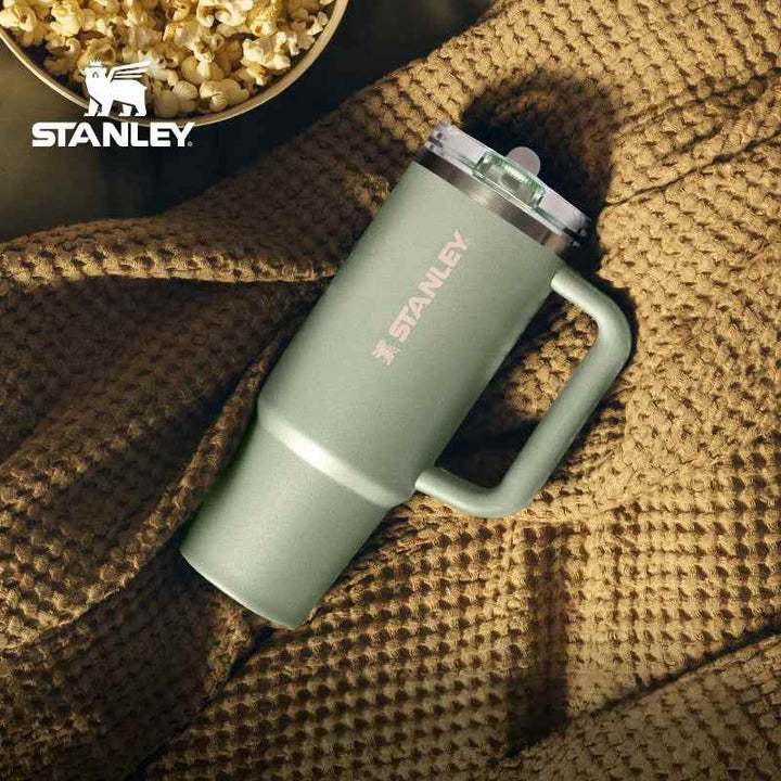 Stanley green stainless steel insulated travel mug with handle on textured brown fabric background