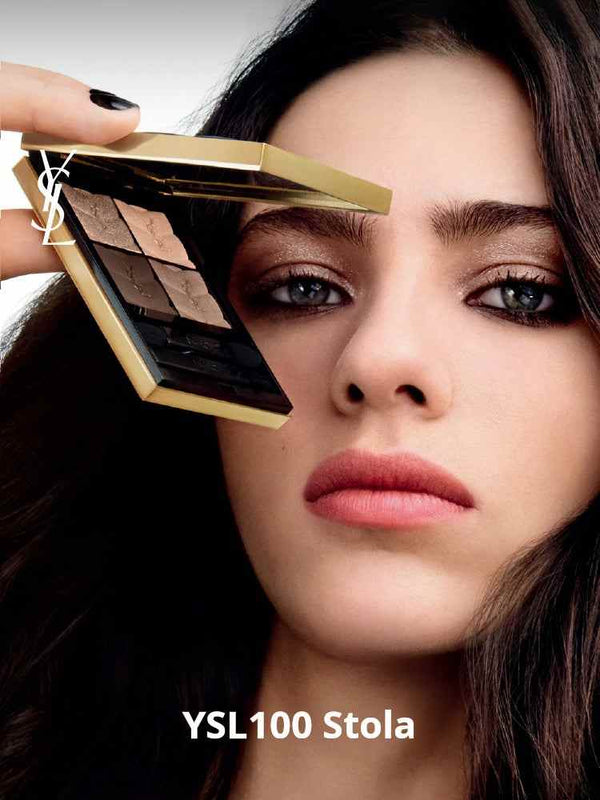 Close-up of a woman holding YSL Couture Color Eyeshadow palette with warm and neutral shades near her eye