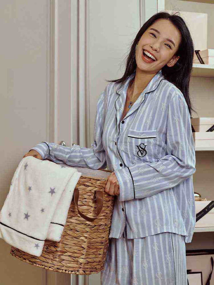 Woman wearing Victoria's Secret star staycation soft print long sleeve Tencel loungewear pajamas holding a basket with a star-printed blanket