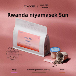 A product display of xBloom xpods featuring the Rwanda Niyamasek Sun specialty coffee. The image shows a white coffee bag branded 'wunder Wanda' alongside eco-friendly كبسولات إكسبلوم and loose coffee beans on a pink background.
